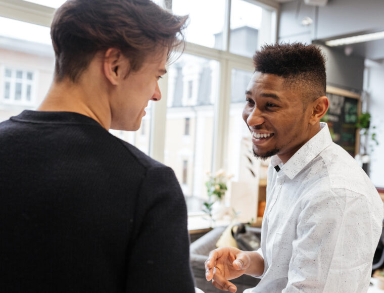 Two young men talking in an open plan living area