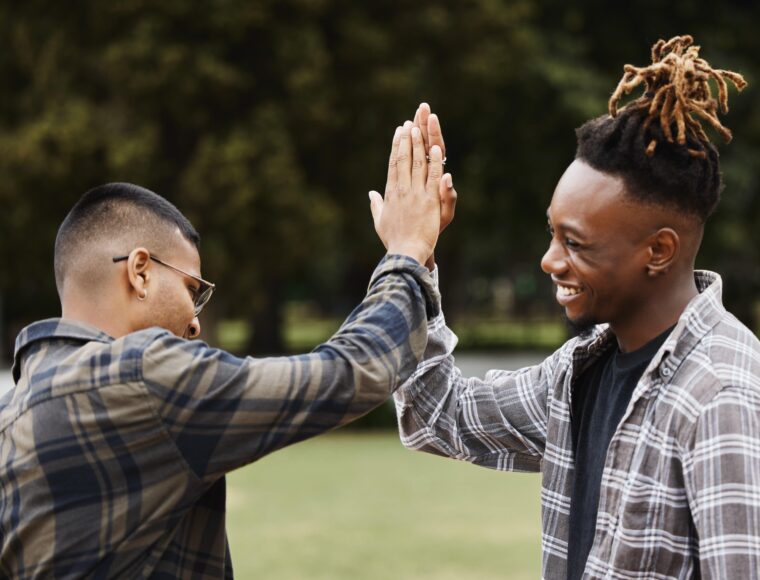 Two young men high fiving in an outdoors setting