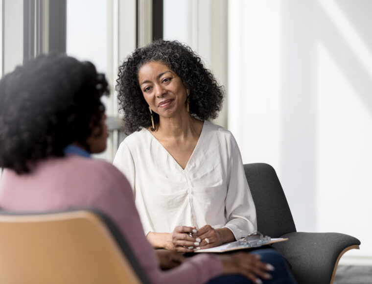 Two adult women talking in an indoor setting.