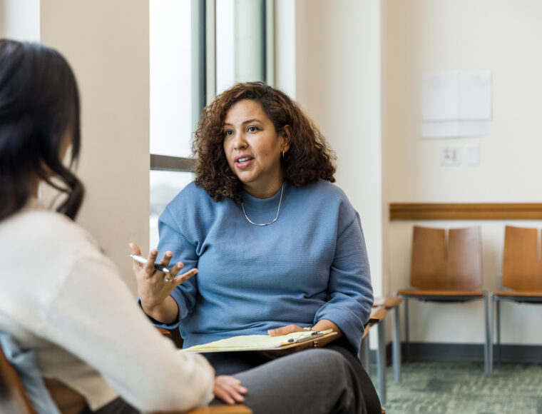 Female therapist gestures while talking with the unrecognizeable woman