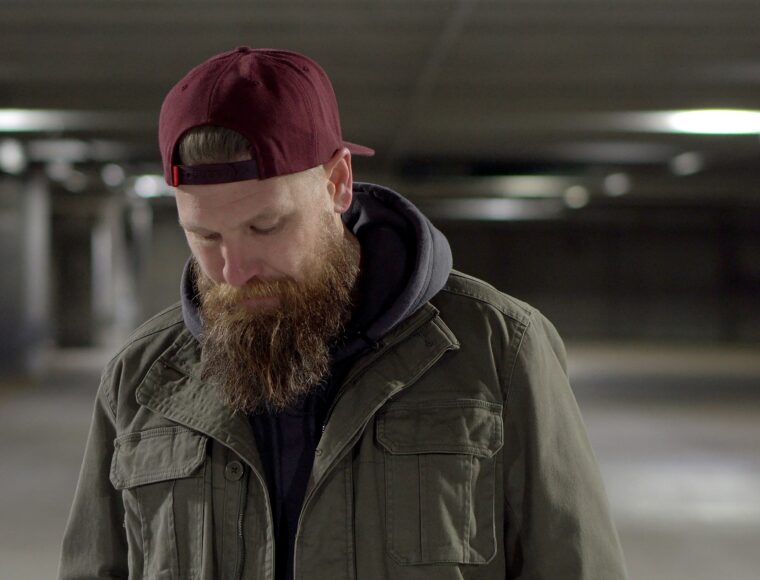 Photo of a man wearing and jacket and a baseball hat